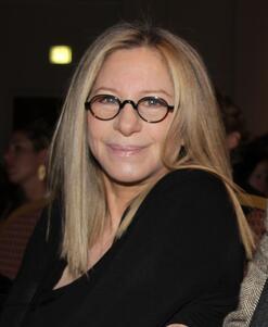 Barbra Streisand at the"Health Matters" Conference, smiling in dark rimmed glasses