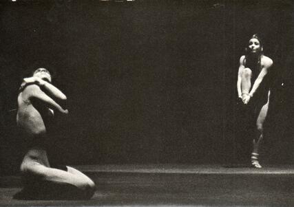 Cecilia Baram dancing, balancing on one foot, while Miguel Angel Palmeros kneels on the other side of the stage