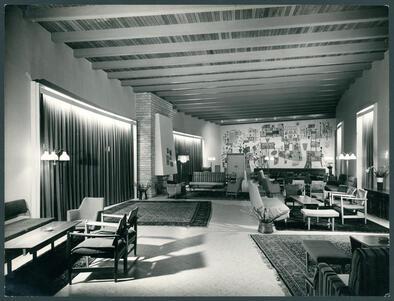 A hotel lobby with seating and rugs, and a painted mural