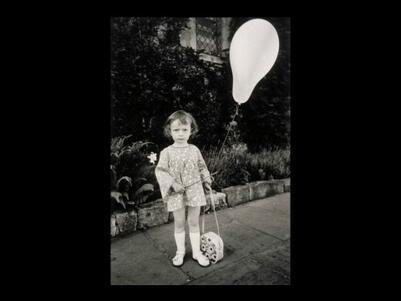 A young girl holding a flower purse and a balloon on a stick