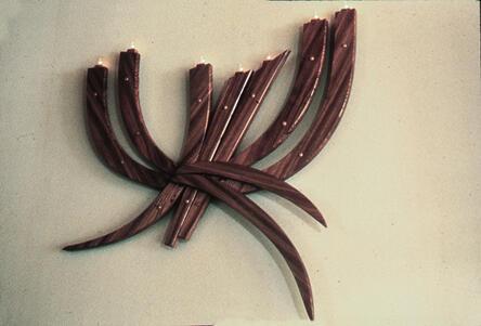A menorah mounted on the wall, made of nine curved pieces of wood