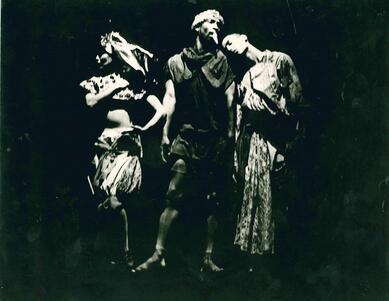 Three dancers in tribal clothing standing together onstage