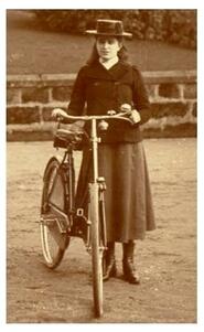 A young Vera Salomons, wearing a coat, skirt, and hat, with a bike
