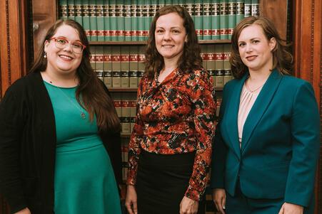 Photo of three women standing in front of a bookcase