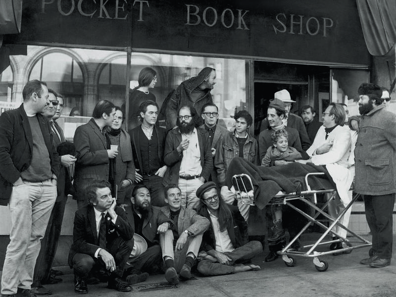 A group of people in three rows in front of a bookstore. 