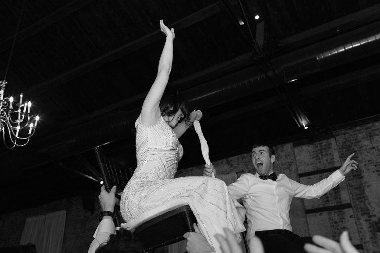Bride and groom lifted in chairs at their wedding