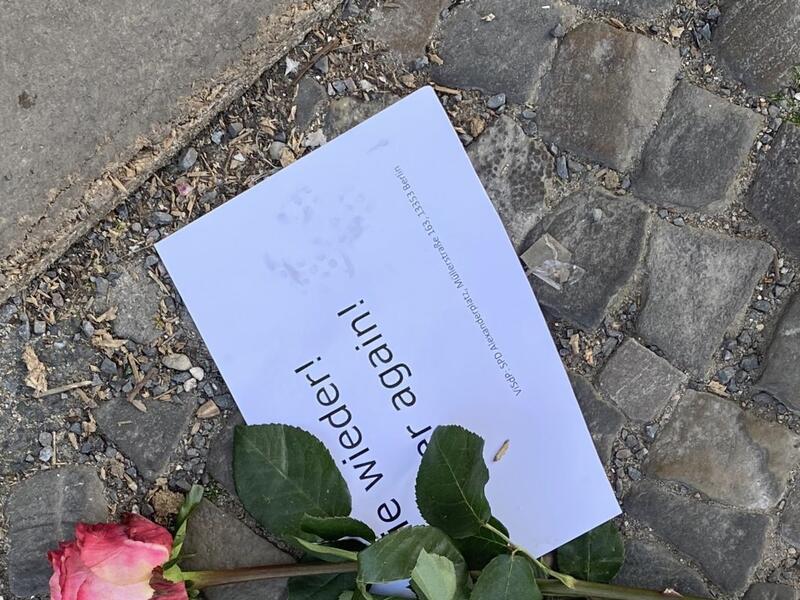 Berlin "Stumbling Stone" to commemorate Holocaust victim with rose and sign reading "never again" placed on top