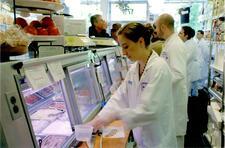 Niki Russ Federman in a white work coat preparing food behind the counter at Russ & Daughters