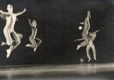 Four dancers leaping in the air, striking the same pose with extended arms and folded legs