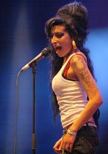Amy Winehouse singing into a microphone at Eurockéennes rock festival with iconic beehive hair and winged liner