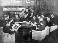 A group of seated people around a table in a Production Team meeting