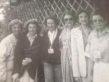 Six women pose in front of a garden trellis