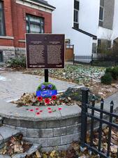 A plaque dedicated to Lillian Freiman, with poppies and a "Lest We Forget" wreath at its base