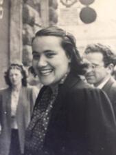 Matilde Cassin standing on the street and smiling, with a man and woman in the background