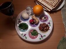 A seder plate with the six traditional items and an orange.