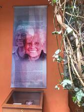 A hanging panel with photos of Rita Arditti on the wall above an exhibit box