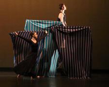 Dancers on stage performing with large squares of striped fabric