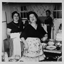 Black and white photo of three women laughing in a kitchen