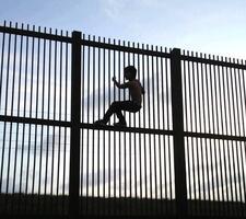 A Child Climbing a Fence at Mexico-US Border Cropped