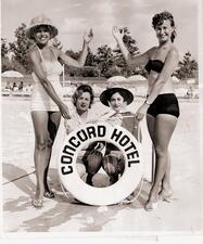 Four women standing by a pool with a life preserver that says Concord Hotel
