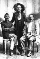 Sonja Schlesin standing, with Gandhi and Dr. Hermann Kallenback seated