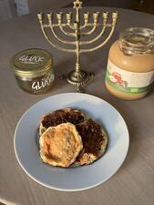 A plate of latkes with jars of applesauce and honey and a menorah