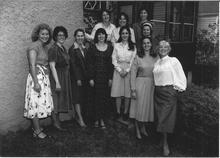 A group of eleven women posing together in a courtyard
