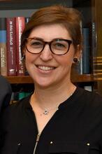 Mayim Bialik standing in front of a bookshelf with Jewish books