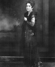Studio portrait of actress Mirra Eitingon standing in a black dress