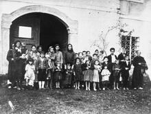 A large group of women and children standing in front of an open doorway