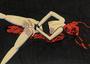 Image of naked women with arms tied behind her back, blood on her face and body, against a black backround