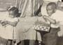 Black and white photo of Black woman sitting with grandchildren on either side of her