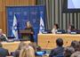 Women speaks at podium with Israeli flags in background