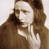 A promotional portrait of Hanna Rovina, looking concerned with her hand touching her face