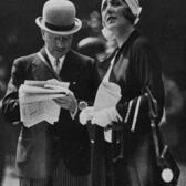 Germaine de Rothschild standing beside André Citroën, reading a newspaper