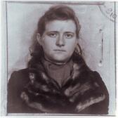 A square photo of young Haika Grossman, wearing a fur collar coat, with a stamp in the corner