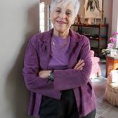 Lynn Schusterman leaning against a wall in front of a sitting room