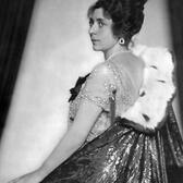 Over-the-shoulder portrait of Fritzi Massary, wearing an ermine-trimmed cape, a lace dress, and jewels