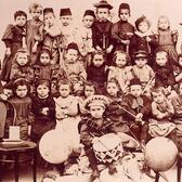 Group photo of kindergarteners, with woman teacher at left 
