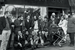 A group of people in three rows in front of a bookstore. 