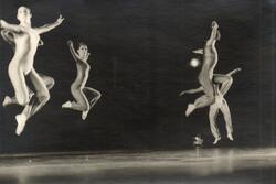 Four dancers leaping in the air, striking the same pose with extended arms and folded legs