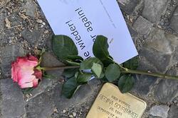 Berlin "Stumbling Stone" to commemorate Holocaust victim with rose and sign reading "never again" placed on top