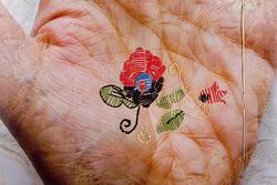 Photograph of a hand with flower embroidered on it