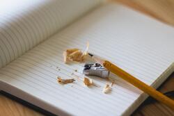 Pencil with sharpener resting on a notebook.