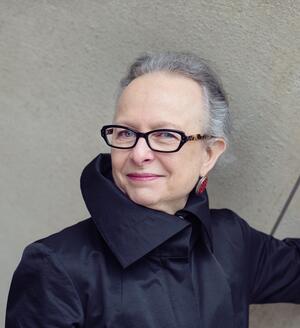 Barbara Kirshenblatt-Gimblett smiling, wearing a black, high collar top and glasses