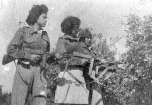 Three women in uniform stand holding rifles