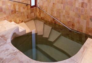 Interior of Mayyim Hayyim mikveh in Newton, Massachussetts showing stairs with handrail going into the water