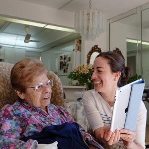 Niki Russ Federman smiling and holding up an iPad to her grandmother Anne Russ Federman