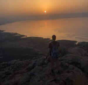 Sunrise over the Kinneret in Israel. Figure in the foreground on rocks.