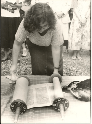 A woman leaning over to read from a Torah scroll